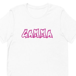 May include: White t-shirt with a pink "GAMMA" graphic in a graffiti style font.