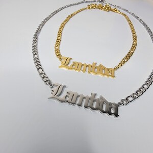 May include: Two silver chains with a silver and gold nameplate pendant that reads "Lambda".