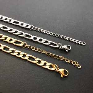 K&ouml;nnte beinhalten: Drei goldene und silberne Kettenhalsb&auml;nder mit Karabinerverschl&uuml;ssen. Die Ketten haben unterschiedliche L&auml;ngen und Breiten.