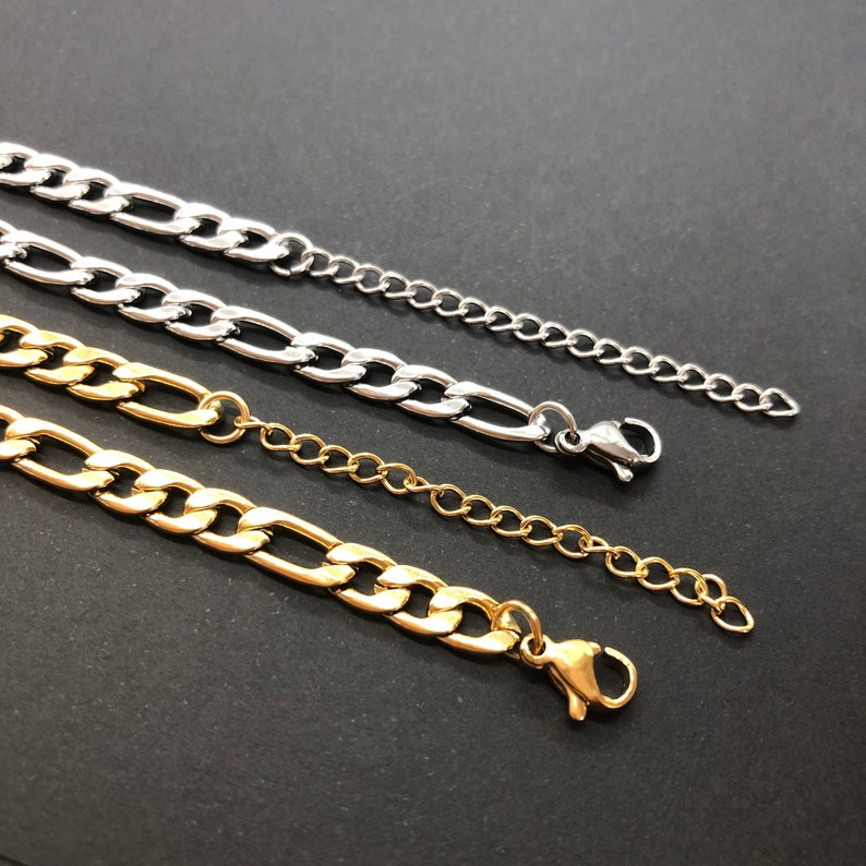 K&ouml;nnte beinhalten: Drei goldene und silberne Kettenhalsb&auml;nder mit Karabinerverschl&uuml;ssen. Die Ketten haben unterschiedliche L&auml;ngen und Breiten.