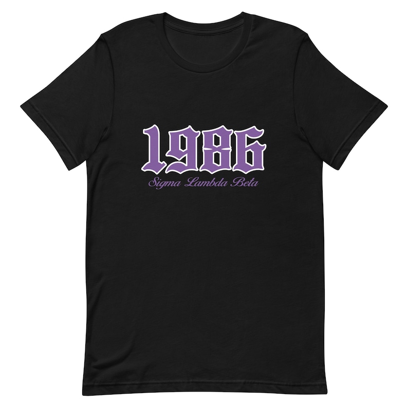Op de afbeelding: Zwart T-shirt met een paarse 1986 in gotische letter en de tekst "Sigma Lambda Beta" eronder.
