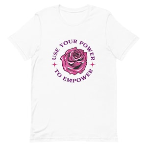 May include: White t-shirt with a purple circle graphic featuring a pink rose and the text "Use your power to empower".
