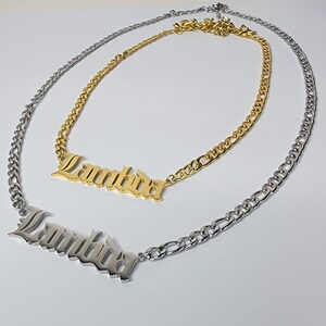 May include: Two gold and silver chains with the word "Lambda" spelled out in old English lettering on each chain.