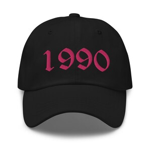 May include: Black baseball cap with a pink embroidered '1990' in a gothic font.