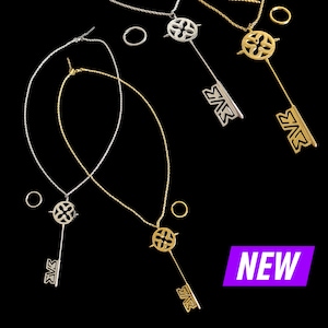 Puede incluir: Tres collares de plata y oro con un dije de llave decorativo. Los dijes de llave tienen un diseño floral y la palabra "NEW" está impresa en un fondo morado.