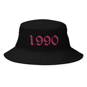 May include: Black bucket hat with a pink 1990 in a gothic font.