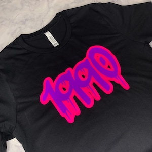 May include: Black t-shirt with a pink and purple graphic that says "1990" in a dripping style.