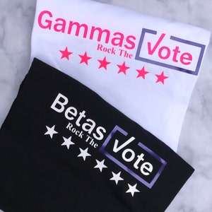 May include: Two t-shirts, one black and one white, with the text "Gammas Vote Rock The" and "Betas Vote Rock The" printed on them. Each shirt has five white stars printed below the text.