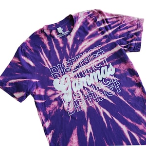 May include: Purple tie-dye t-shirt with white text that reads "Distinct Gammas" in a stacked, repeating pattern.
