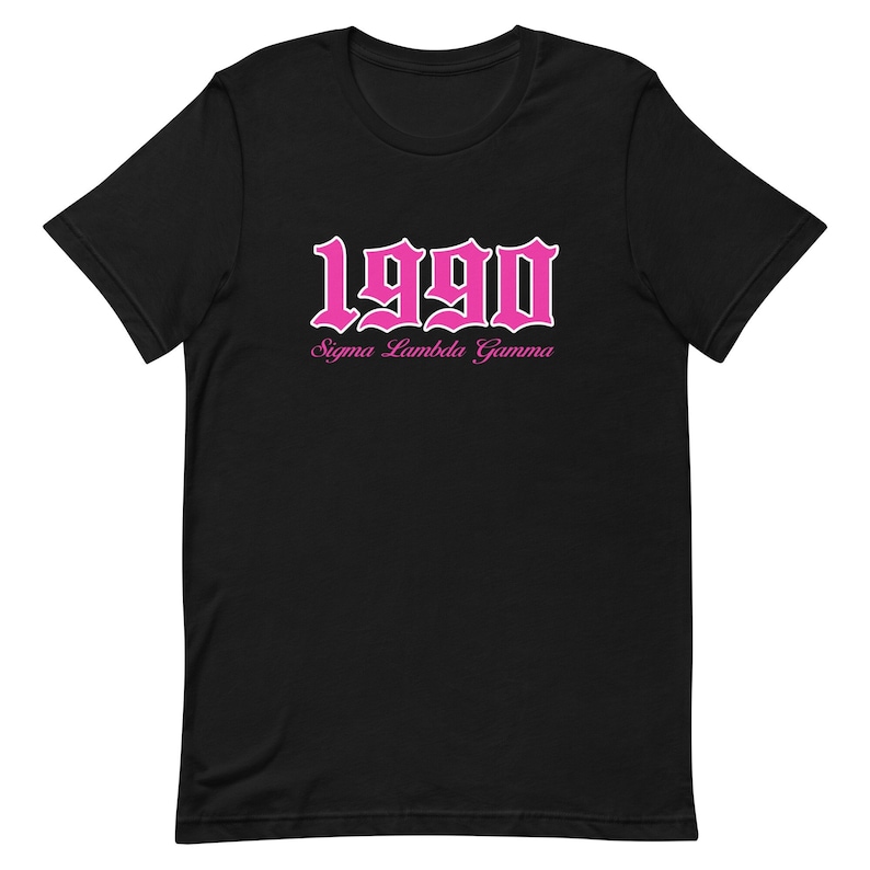 Op de afbeelding: Zwart T-shirt met een roze 1990 in gotische letter en de tekst "Sigma Lambda Gamma" eronder.