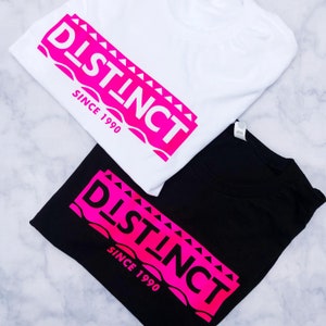 May include: Two t-shirts, one white and one black, with a pink graphic design that says "DISTINCT" and "SINCE 1990".