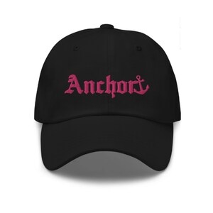 May include: Black baseball cap with a pink embroidered anchor and the word "Anchor" in a gothic font.