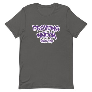 Op de afbeelding: Een donkergrijs T-shirt met een paarse grafische afbeelding met de tekst "Providing Wisdom Since 1986".