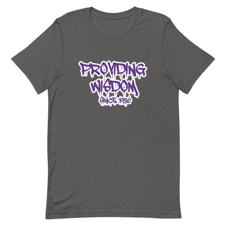 Op de afbeelding: Een donkergrijs T-shirt met een paarse grafische afbeelding met de tekst "Providing Wisdom Since 1986".