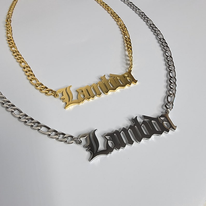 May include: Two gold and silver necklaces with the name "Lambda" spelled out in a gothic font.