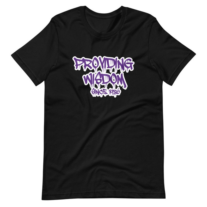 Op de afbeelding: Zwart T-shirt met een paarse grafische afbeelding met de tekst "Providing Wisdom Since 1986".