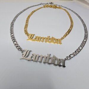 May include: Two silver chain necklaces with a silver and gold nameplate pendant that reads "Lambda".