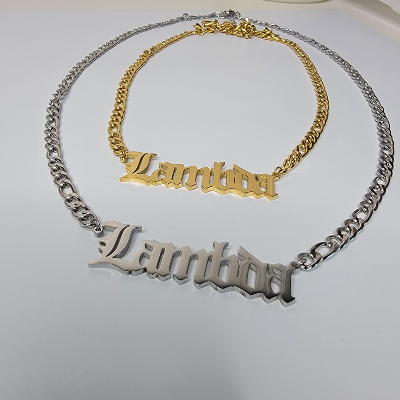 May include: Two silver chain necklaces with a silver and gold nameplate pendant that reads "Lambda".