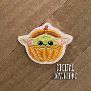 May include: Embroidered patch of a green character with large eyes, wearing a brown and orange pumpkin costume. The character is sitting inside the pumpkin. The patch is white with a white outline.