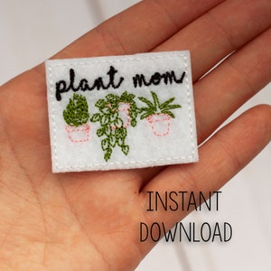 May include: White felt patch with black embroidery that reads "plant mom" and features three green potted plants.