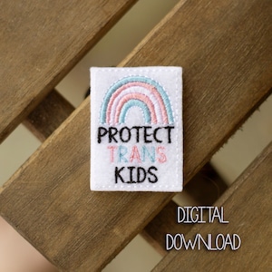Könnte beinhalten: Weißer Filz-Patch mit einem Regenbogen-Design und dem Text "PROTECT TRANS KIDS" in schwarzer Stickerei.