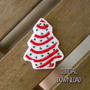 May include: A white felt Christmas tree applique with red and green embroidery. The tree has a striped pattern with red stripes and green dots.