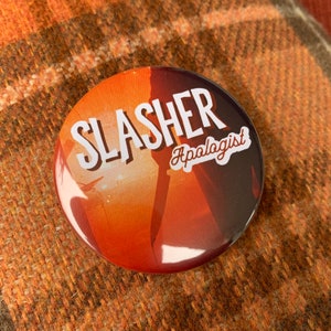 May include: A round button with an orange and red background featuring the text "SLASHER Apologist" in white.