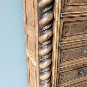 Puede incluir: Una c&oacute;moda alta de madera que presenta una prominente columna vertical con forma de espiral en el lateral. La pieza est&aacute; hecha de madera de color marr&oacute;n claro con vetas visibles e incluye varios cajones con peque&ntilde;os pomos redondos.