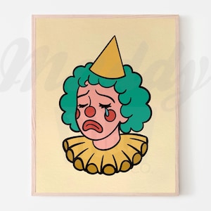 Puede incluir: Una impresión enmarcada con una ilustración de un payaso triste. El payaso tiene cabello rizado verde azulado, un sombrero de cono amarillo y un cuello con volantes. Lágrimas rojas caen de los ojos del payaso y la cara del payaso está pintada con círculos rojos.
