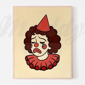 Puede incluir: Impresión enmarcada con una ilustración de un payaso triste. El payaso tiene cabello rizado marrón, una nariz roja y una lágrima rodando por su mejilla. Lleva un gorro de fiesta rojo y un cuello con volantes, sobre un fondo crema.