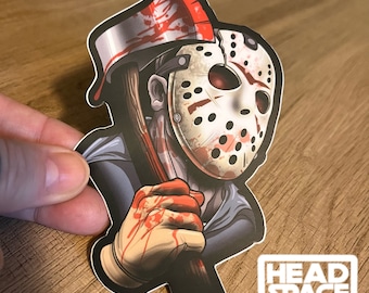 May include: A sticker featuring a graphic illustration of a hockey mask-wearing figure holding a bloody axe. The figure is wearing a blue and grey shirt. The sticker has a white border and the text "HEADSPACE GRAPHICS" at the bottom.