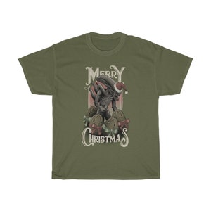 May include: A green t-shirt with a vintage-style illustration of an alien wearing a Santa hat and holding Christmas ornaments. The text "Merry Christmas" is printed below the alien.