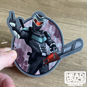 May include: A black and teal character with a red visor and a chainsaw, against a pink and purple background. The character is giving a middle finger. The sticker says "HEADSPACE GRAPHICS" at the bottom.