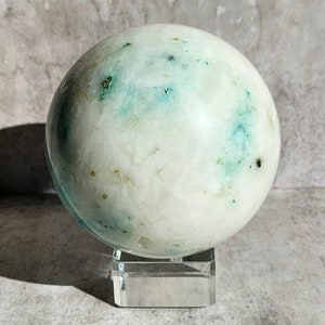 Sphère d'amazonite à matrice blanc-gris et accents turquoise. Une pièce claire et polie, à l'aspect serein et à la brillance douce.