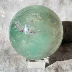 Sphère de fluorite vert pastel avec une lueur presque translucide. Améliore la clarté, la paix intérieure et l’équilibre. Source de calme qui approfondit la concentration.