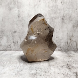 Quartz fumé de forme libre avec inclusions naturelles. Favorise l'ancrage et la purification mentale. Cristallin et géologiquement fascinant.