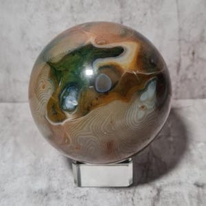 Sfera di Ocean Jasper: motivi ondulati e tonalità terrose. Favorisce l'equilibrio emotivo, la pazienza, la guarigione e incoraggia la comunicazione amorevole.