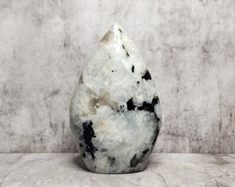 Rainbow Moonstone with black Tourmaline. White base with black inclusions and blue flashes. Raw energy in polished form.