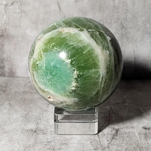 Sfera di onice verde che dona pace, concentrazione e forza. Splendidamente lucidato con bande naturali: un gioiello energeticamente potente che cattura lo sguardo.
