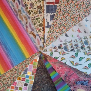 May include: A collection of colorful patterned wrapping paper featuring various designs, including feathers, stripes, butterflies, and city skylines. The papers are arranged in a fan shape, with the tips of each paper meeting in the center.