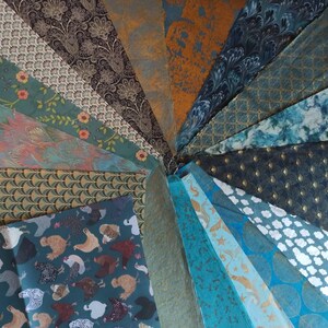 May include: A collection of 20 different patterned wrapping papers in shades of teal, blue, brown, and gold. The papers feature various designs, including geometric patterns, floral motifs, and animal prints.