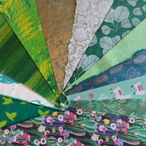 May include: A collection of green patterned papers with various designs, including marbled, floral, and geometric patterns. The papers are arranged in a fan shape, showcasing the different textures and colors.