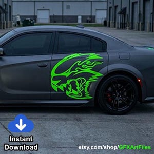 May include: A matte grey sedan featuring a large, bright neon green vinyl decal on the side door. The decal displays a stylized, aggressive creature head design with flame-like details. The car has black wheels and a low-profile body design.
