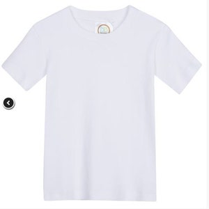 May include: A plain white t-shirt with a small, round label on the front.