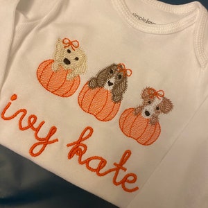Pode incluir: Macac&atilde;o branco para beb&ecirc; com ab&oacute;boras e c&atilde;es bordados. O texto "ivy kate" est&aacute; bordado abaixo das ab&oacute;boras.