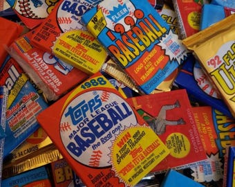 May include: A close-up of a pile of vintage baseball trading cards from the 1980s and 1990s. The cards feature various baseball players and teams, including Topps, Fleer, and Upper Deck. The cards are in various colors, including red, blue, yellow, and green.
