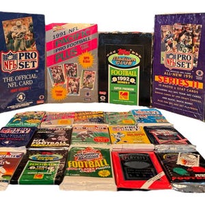 May include: A collection of unopened boxes of 1991 and 1992 Pro Set NFL trading cards. The boxes are arranged in a row, with the 1991 boxes on the left and the 1992 boxes on the right. The boxes are all in good condition and have a variety of colors and designs. There are also several packs of trading cards in the foreground.