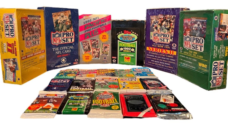 May include: A collection of unopened boxes of 1991 and 1992 Pro Set NFL trading cards. The boxes are arranged in a row, with the 1991 boxes on the left and the 1992 boxes on the right. The boxes are all in good condition and have a variety of colors and designs. There are also several packs of trading cards in the foreground.
