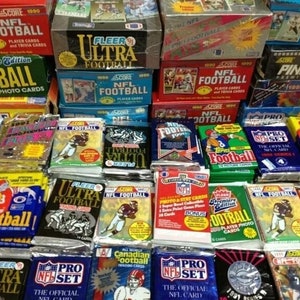May include: A collection of various unopened packs of NFL football trading cards from the 1990s. The packs feature different brands, including Score, Fleer, Pinnacle, and Pro Set. Some packs have player photos, while others have team logos.