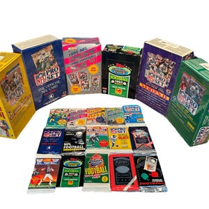 May include: A collection of unopened packs of 1991 and 1992 NFL Pro Set trading cards. The packs are arranged in a semi-circle with the newer packs in the front. The packs are all in various colors, including red, blue, green, and yellow. The packs feature the NFL Pro Set logo and the year of the cards.